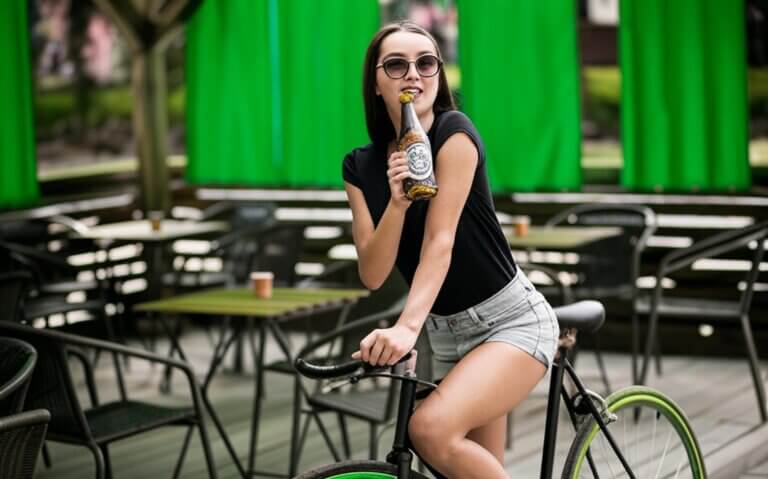 Frau auf einem Fahrrad mit einer Bierflasche