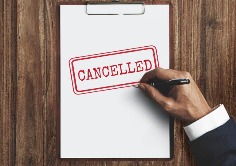Mensch schreibt Cancelled auf ein Blatt Papier